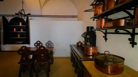 Kitchen of the old castle. Copper pans, baking molds and other kitchen utensi Stock Photos