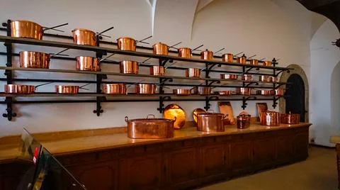 Kitchen of the old castle. Copper pans, baking molds and other kitchen utensi Stock Photos