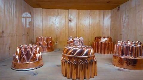 Kitchen of the old castle. Copper pans, baking molds and other kitchen utensi Stock Photos