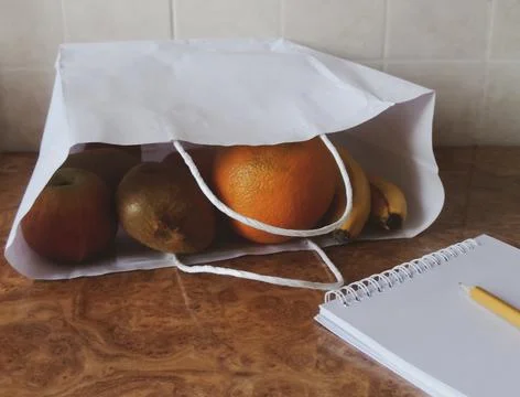 At kitchen: paper bag, fruits, notebook, pencil. shopping concept Stock Photos