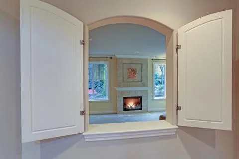 Kitchen pass through window opens to a living room with a main focus on a fir Stock Photos