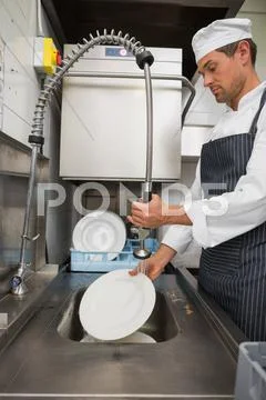 Kitchen Porter Cleaning Plates In Sink