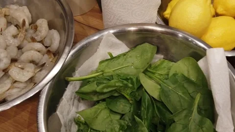 Kitchen prep with shrimp, spinach, leeks, and assorted citrus ingredients Stock Footage 330138570