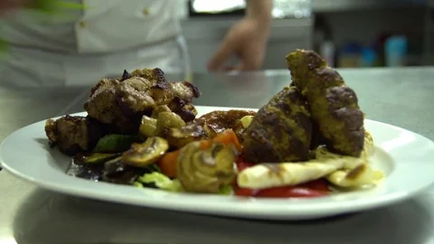 Kitchen. Restaurant. Cooking. The chef decorates grilled meat with vegetables Stock Footage 73955401