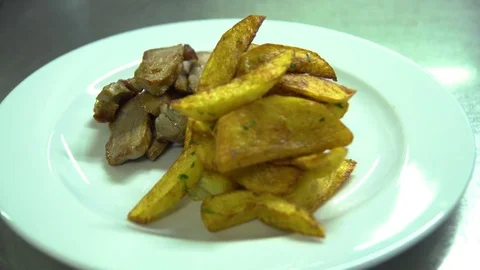 Kitchen. Restaurant. Cooking. Chef pours sauce on the meat and potatoes on a Stock Footage 73955016