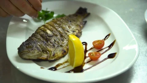 Kitchen. Restaurant. Cooking. The chef puts the greens on a plate with the fish Stock Footage 73954620