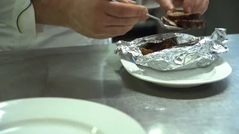Kitchen. Restaurant. Cooking. The cook puts meat baked in foil, on a platter Video stock 73955048