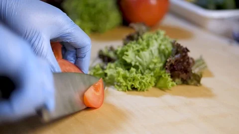 In the kitchen of the restaurant man cuts tomato for salad. lettuce Stock Footage 126752415
