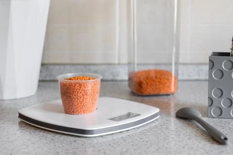 Kitchen scale with measuring cup with red lentils on the kitchen desktop Stock Photos