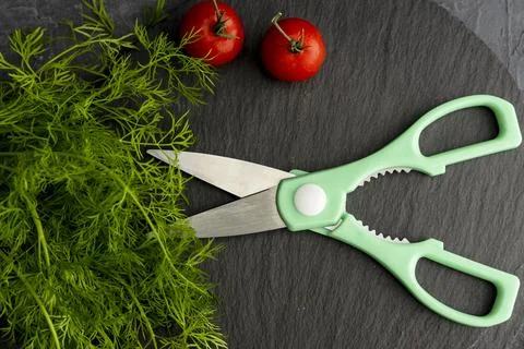 Kitchen scissors cutting dill in the kitchen on a cutting board Stock Photos