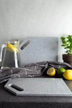 Kitchen setup with gray stone cutting boards, lemons and limes, glass pitcher Stock Photos