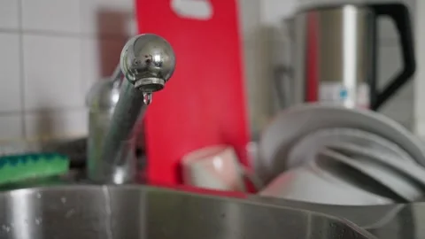 A kitchen sink featuring a dripping faucet along with dishes Stock Footage 281512509
