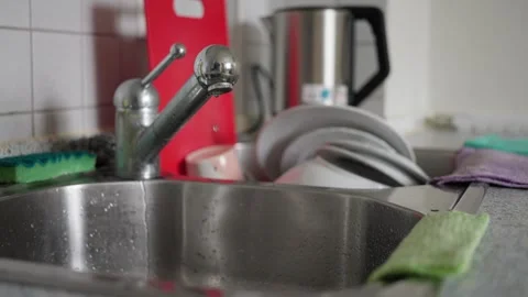 A kitchen sink featuring a dripping faucet paired with a pile of dirty dishes Stock Footage 304684515