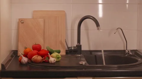 Kitchen sink scene with running water and fresh garden vegetables Stock Footage 340771288