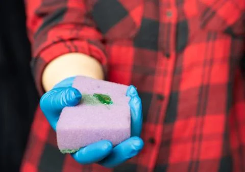 Kitchen sponge with a drop of cleaning agent. Hands of a girl in a hygienic g Stock Photos