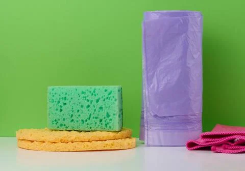 Kitchen sponge, rag and plastic bag roll on green background Stock-Fotos