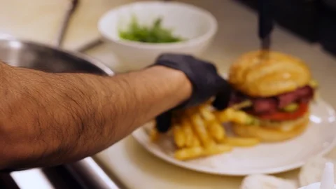 Kitchen staff preparing burger and fries meal Video stock 127930553