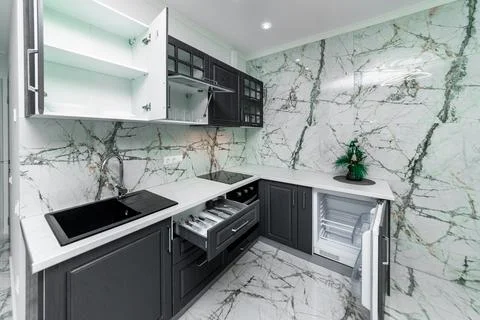 The kitchen in the studio apartment has open drawers with cutlery. Renovati.. Stock Photos