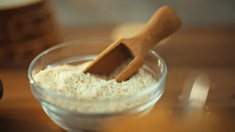 A kitchen table is set with a bowl of sesame seeds and a spice scoop a raw g Stock Footage 331309164