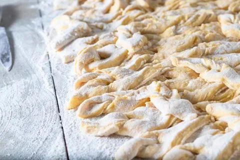 Kitchen table. Sprinkled with flour. On it are dough products. Brushwood. Clo Stock Photos