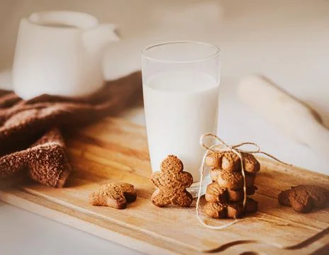 On the kitchen table there is a board on which there is a glass of milk and t Stock Photos