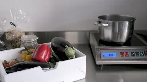 A kitchen table with vegetables, a saucepan and an electric stove. Stock Footage 155076218