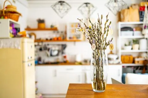 On the kitchen table wooden Easter eggs are placed on the branches Stock Photos