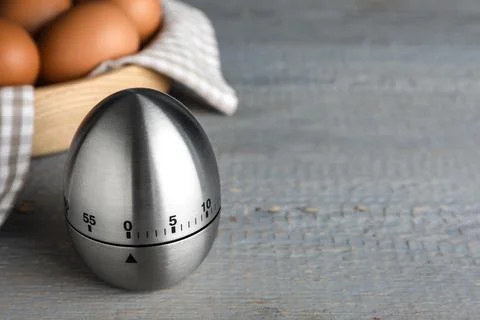 Kitchen timer and eggs on grey wooden table. Space for text Stock-Fotos