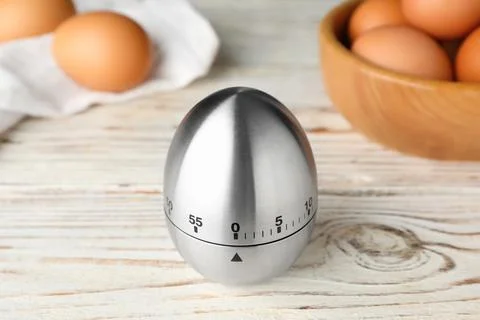 Kitchen timer and eggs on white wooden table Foto stock