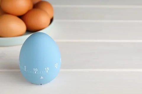 Kitchen timer and eggs on white wooden table. Space for text Foto stock