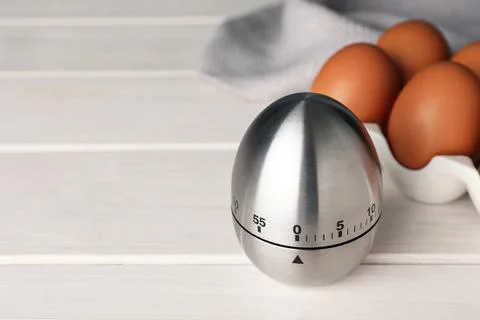 Kitchen timer and eggs on white wooden table. Space for text Stock Photos