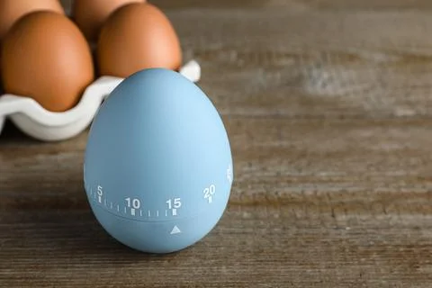 Kitchen timer and eggs on wooden table. Space for text Stock-Fotos