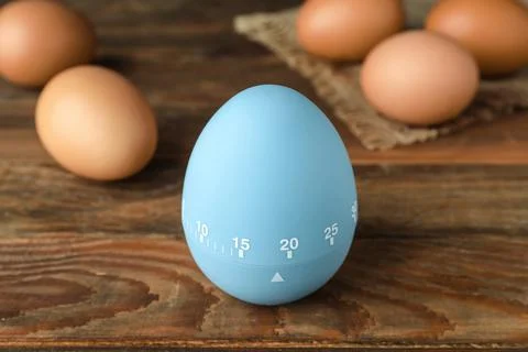 Kitchen timer and eggs on wooden table Stock-Fotos