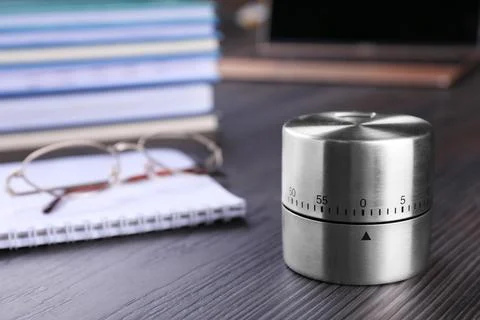 Kitchen timer, notebook and eyeglasses on wooden table, closeup. Space for te Stock Photos