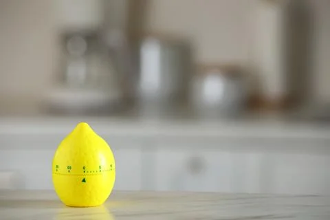Kitchen timer in shape of lemon on white marble table against blurred backg.. Stock Photos