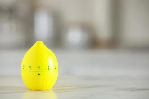 Kitchen timer in shape of lemon on white marble table against blurred backg.. Stock Photos