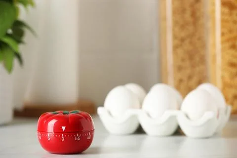 Kitchen timer in shape of tomato and eggs on white table. Space for text Stock Photos