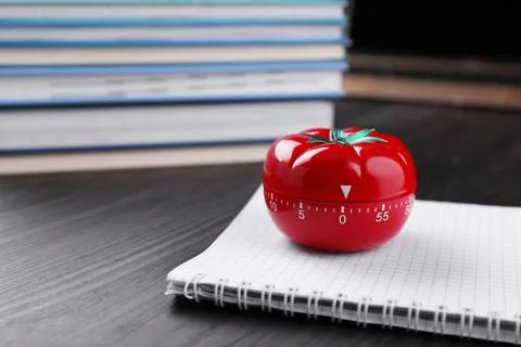 Kitchen timer in shape of tomato and notebook on wooden table, space for text Stock Photos