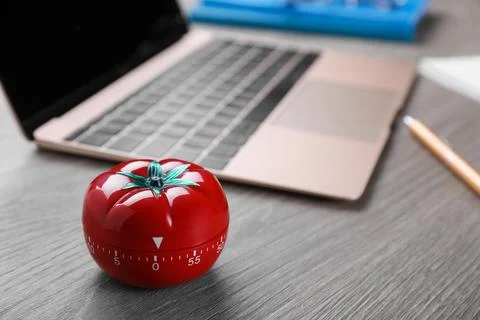 Kitchen timer in shape of tomato and laptop on wooden table, space for text Stock Photos