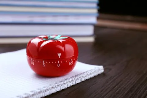 Kitchen timer in shape of tomato and notebook on wooden table, closeup. Spa.. Stock Photos