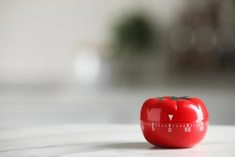 Kitchen timer in shape of tomato on white table against blurred background. S Stock Photos