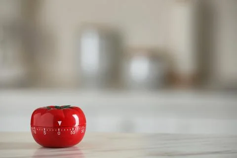 Kitchen timer in shape of tomato on white table against blurred background... Stock Photos