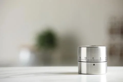 Kitchen timer on white marble table against blurred background. Space for tex Stock Photos