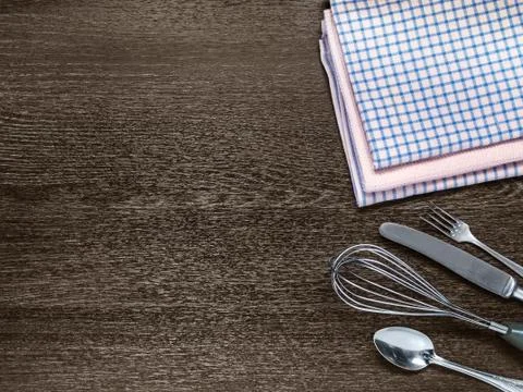 Kitchen towels, fork, spoon, knife, whisk for whipping on wooden background Stock Photos