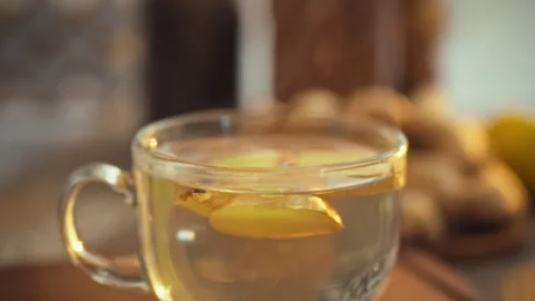 In a kitchen a transparent cup containing sliced ginger swirls releasing pun Video stock 331353035