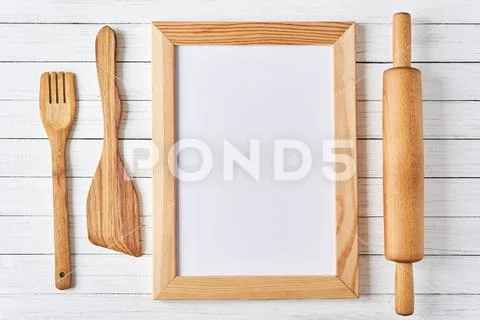 Kitchen utensils and empty sheet in a wooden frame on white background. Kitch Stock Photos