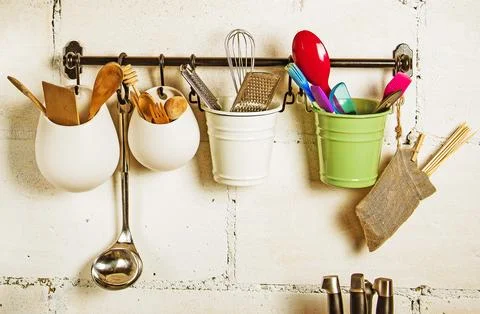 Kitchen utensils.A hanger with multi-colored buckets containing various kitchen Stock Photos