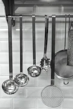 Kitchen utensils hanging on white tiled background. Stock Photos