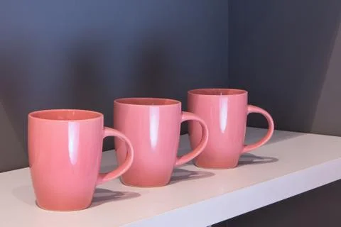 Kitchen utensils three red empty mugs on kitchen shelf close-up - objects wit Stock Photos