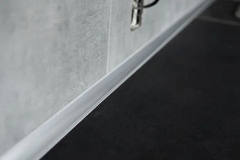 Kitchen wall joint with smooth plastic sealing strip and dark countertop surface Stock Photos